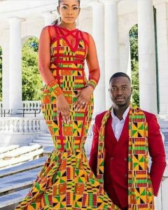 a kente fabric with dark red outfit the man rocked a plain red suit with kente muffler while the bride rocked a full kente gown - humourandstyle